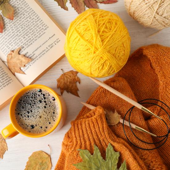 Billedet viser et orange strikketøj og en kop kaffe set ovenfra