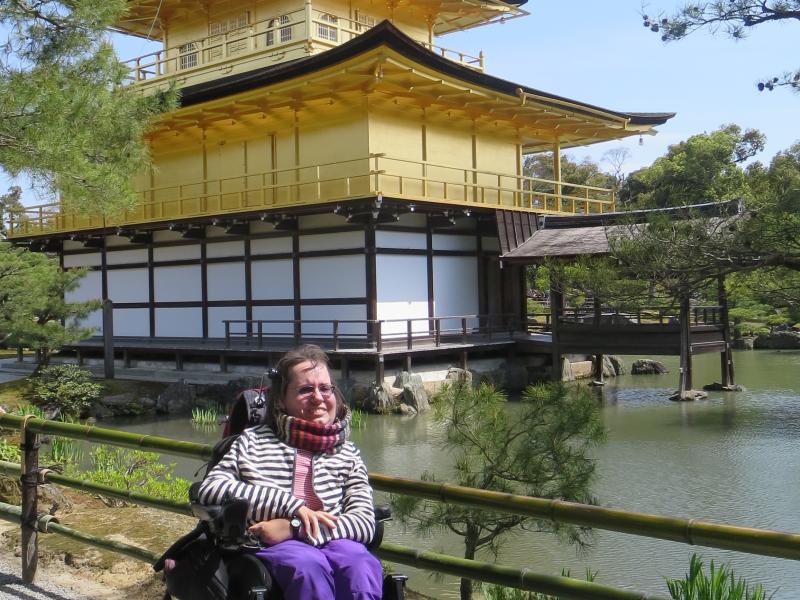 Billedet viser en person i kørestol foran en gylden pavillon i Japan